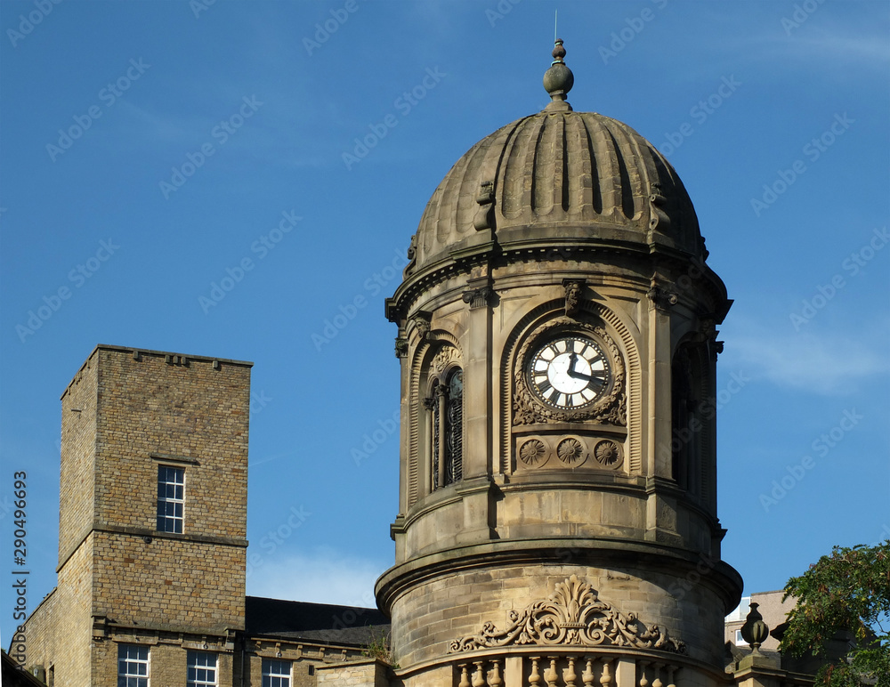 and ornate clock tower with stone cupola against a blue sky on the former sowerby bridge town hall