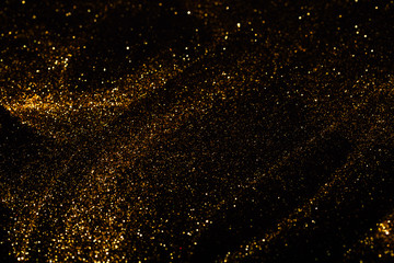 Splash of golden sparkles on black background.