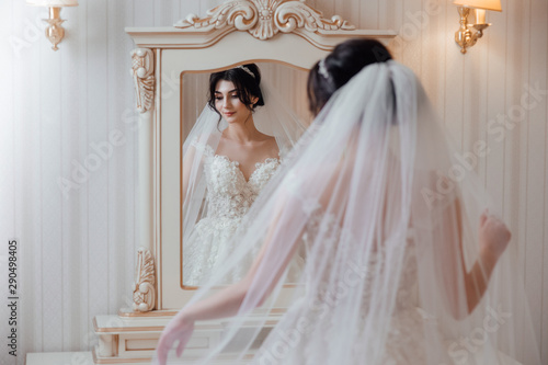 Fotografia Beautiful bride in white dress near a mirror