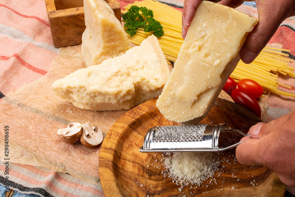 Man cooking with hard italian cheese, grated parmesan or grana padano cheese,  hand with grater Stock Photo | Adobe Stock
