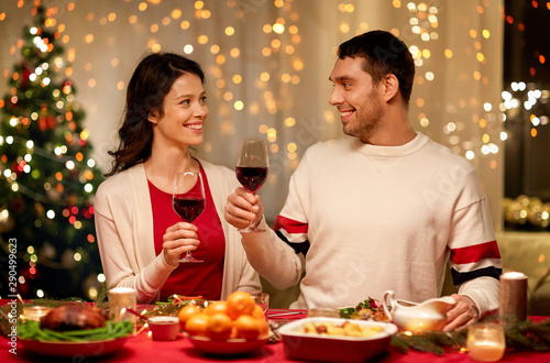 holidays  family and celebration concept - happy couple having christmas dinner at home and drinking red wine
