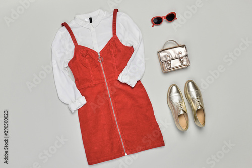 Fall fashion Clothes Accessories Outfit. Autumn mood, creative minimal Flat lay. Trendy red dress, Stylish gold loafers shoes, handbag, fashionable look. Design autumnal fall burgundy color