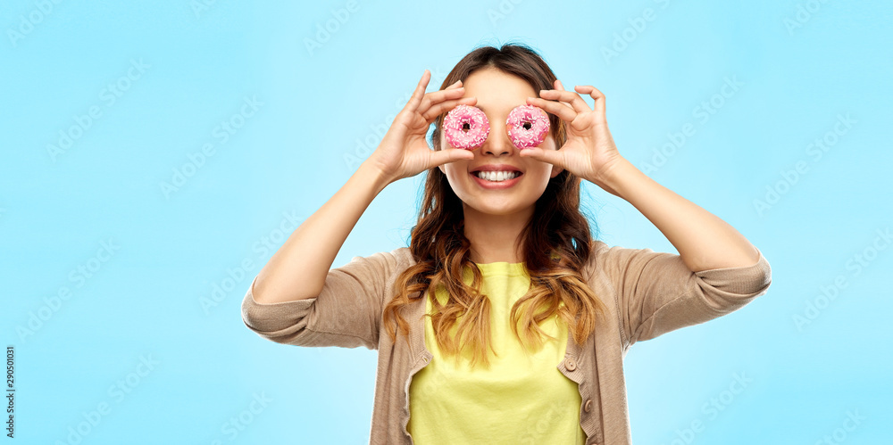 people, fast food and fun concept - happy asian young woman with donuts instead of eyes over blue background people, fast food and fun concept - happy asian young woman with donuts instead of eyes over blue background