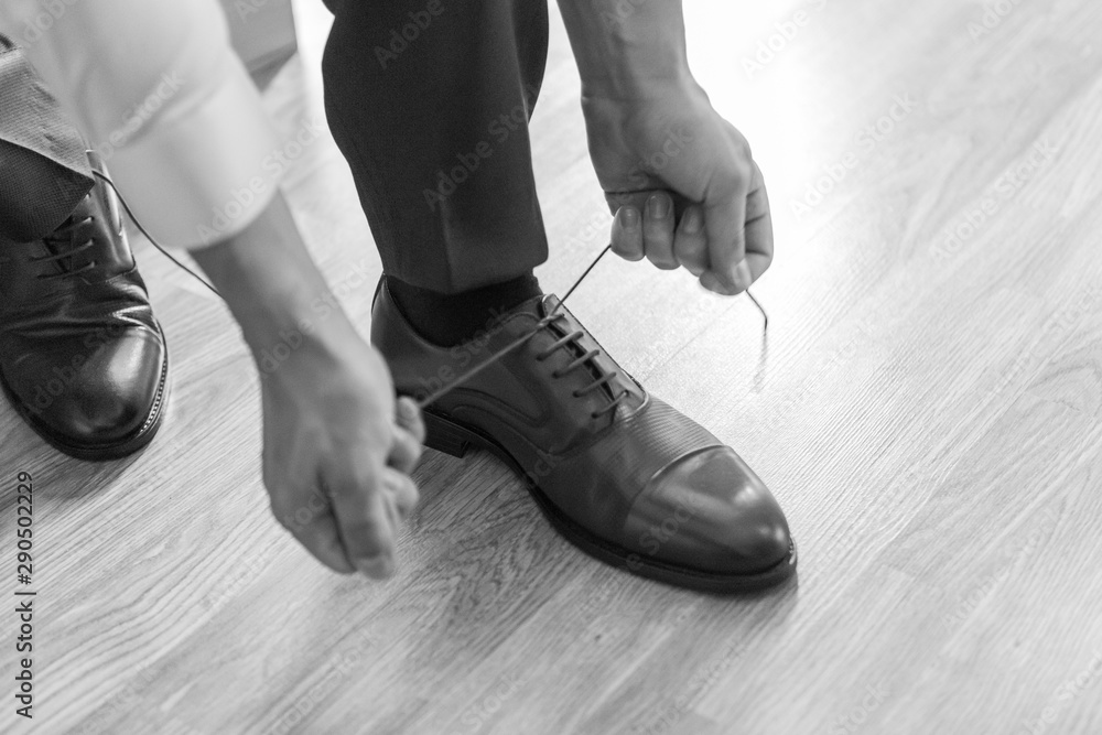 the groom puts on his wedding shoes. a man in a suit puts on his shoes. preparation for the event.