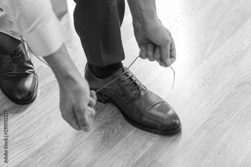 the groom puts on his wedding shoes. a man in a suit puts on his shoes. preparation for the event.