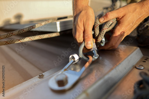 Closeup pic clipping Dynamic low stretch rope rigged with figure of eight knot into screwgate locking carabiner attached into industrial stainless abseiling fall arrest roof anchor point prior to used