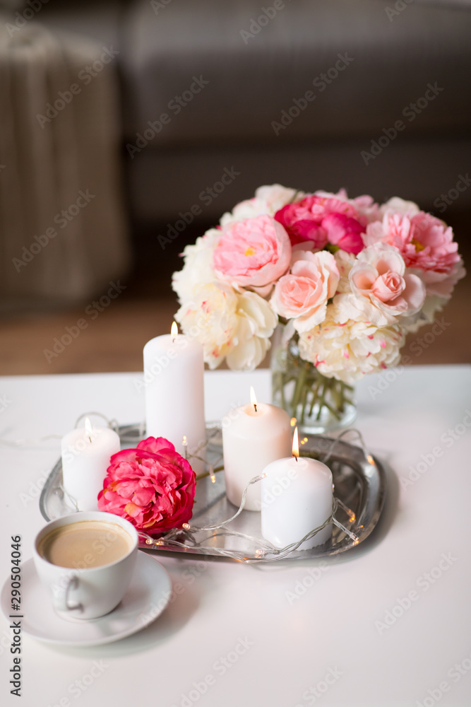 hygge and aromatherapy concept - burning candles, electric garland lights, cup of coffee and flowers on table hygge and aromatherapy concept - burning candles, electric garland lights, cup of coffee and flowers on table