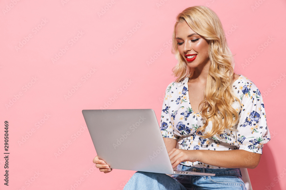 Image of beautiful woman using silver laptop while sitting on chair Image of beautiful woman using silver laptop while sitting on chair