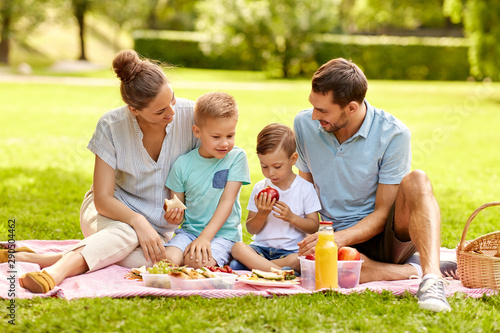 family, leisure and people concept - happy mother, father and two little sons having picnic at summer park © Syda Productions