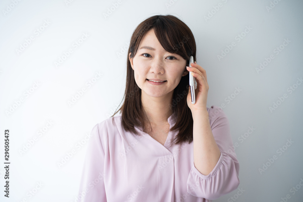 Young business woman talking on smart phone against white wall Young business woman talking on smart phone against white wall