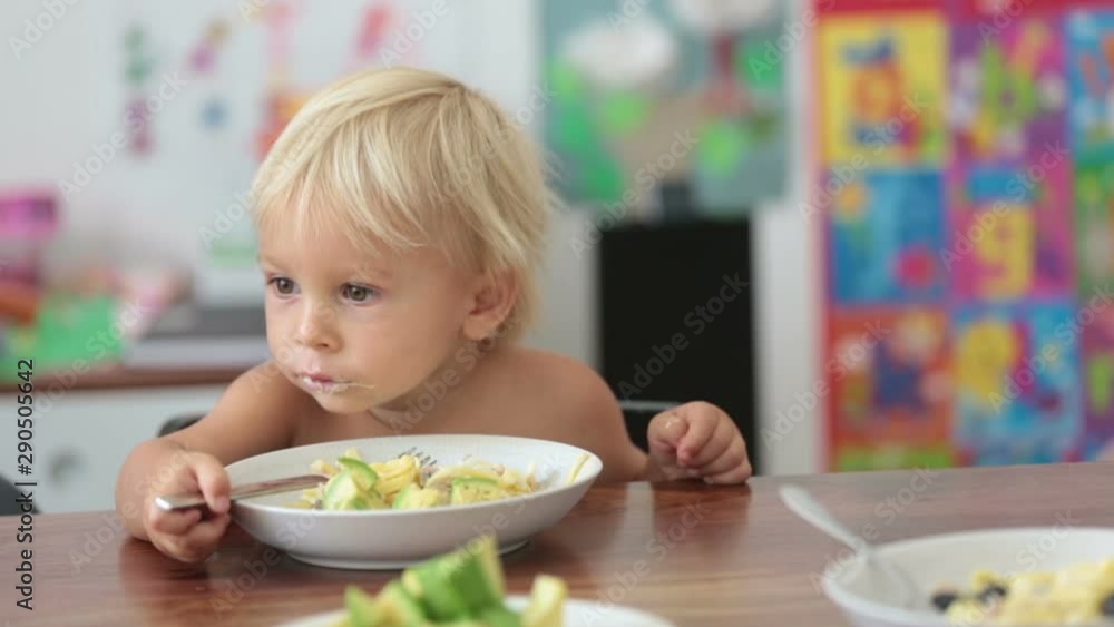 Sweet toddler boy, eating spaghetti at home, making a mess and having fun playing with them Sweet toddler boy, eating spaghetti at home, making a mess and having fun playing with them