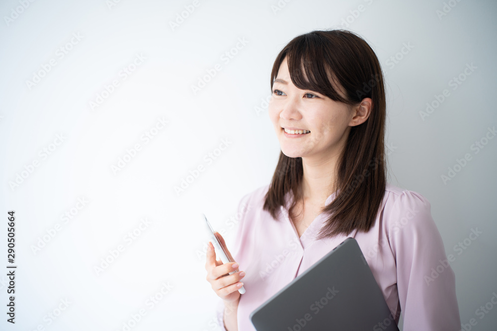 Young business woman holding smart phone and laptop computeragainst white wall Young business woman holding smart phone and laptop computeragainst white wall