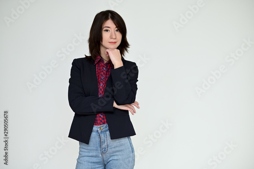 Portrait of a pretty asian brunette girl with black hair in a dark jacket and blue jeans on a white background. It stands right in front of the camera, with emotions in various poses.