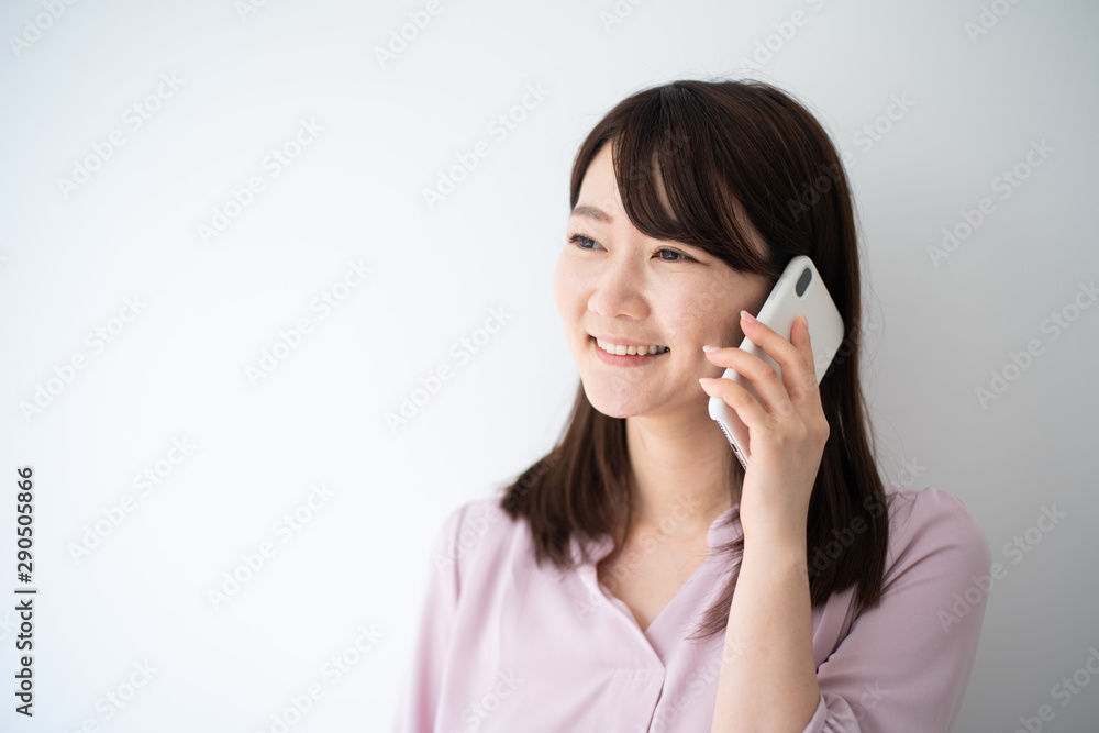 Young business woman holding smart phone against white wall Young business woman holding smart phone against white wall