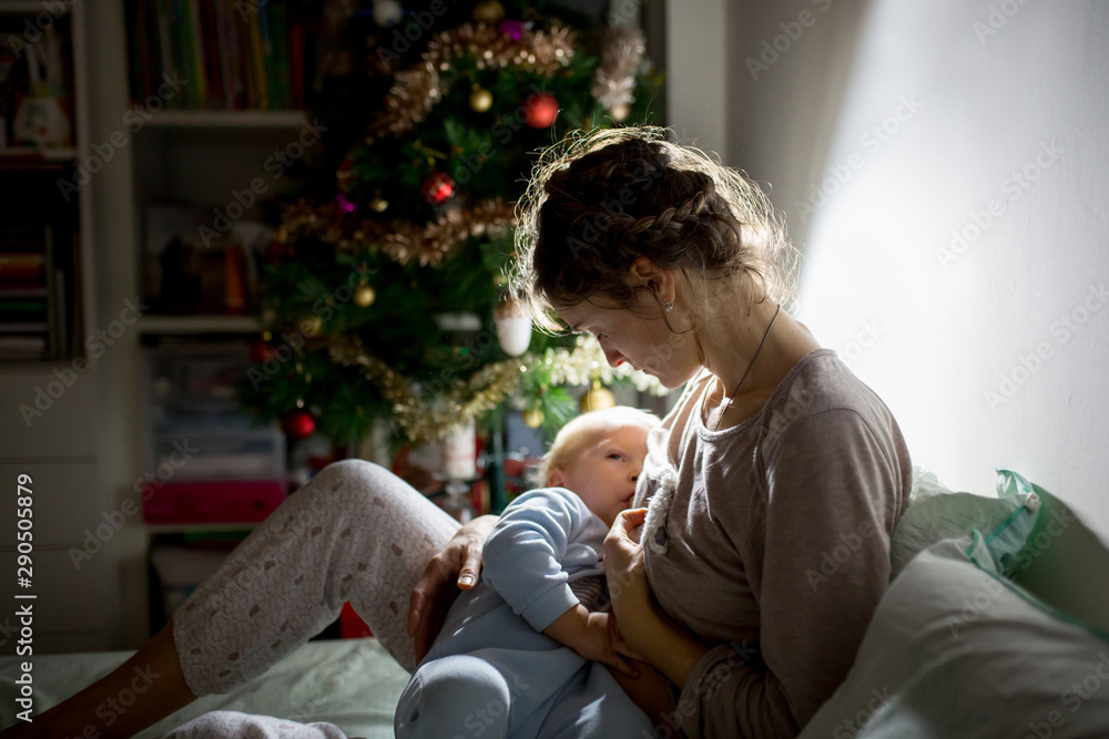 Young beautiful mother, breastfeeding her newborn baby boy at night, dim light. Mom breastfeeding toddler Young beautiful mother, breastfeeding her newborn baby boy at night, dim light. Mom breastfeeding toddler