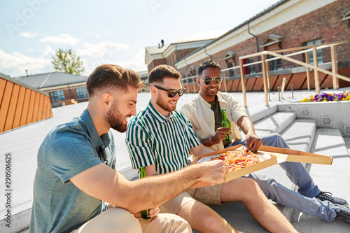 food, leisure and people concept - happy male friends drinking beer and eating takeaway pizza on stairs at rooftop party in summer