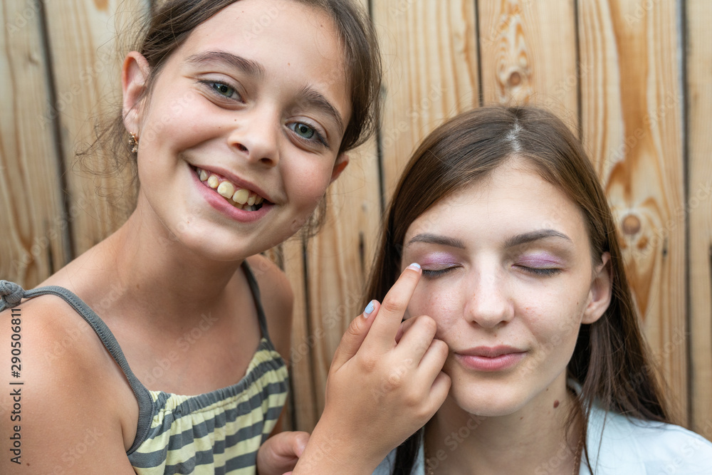 Little smiling brunette girl for the first time did makeup to her sister and pleased with the results Little smiling brunette girl for the first time did makeup to her sister and pleased with the results