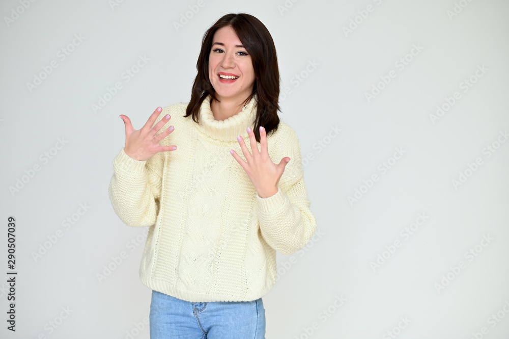 Portrait of a pretty asian brunette girl with black hair in a white sweater and blue jeans on a white background. It stands right in front of the camera, with emotions in various poses. Portrait of a pretty asian brunette girl with black hair in a white sweater and blue jeans on a white background. It stands right in front of the camera, with emotions in various poses.