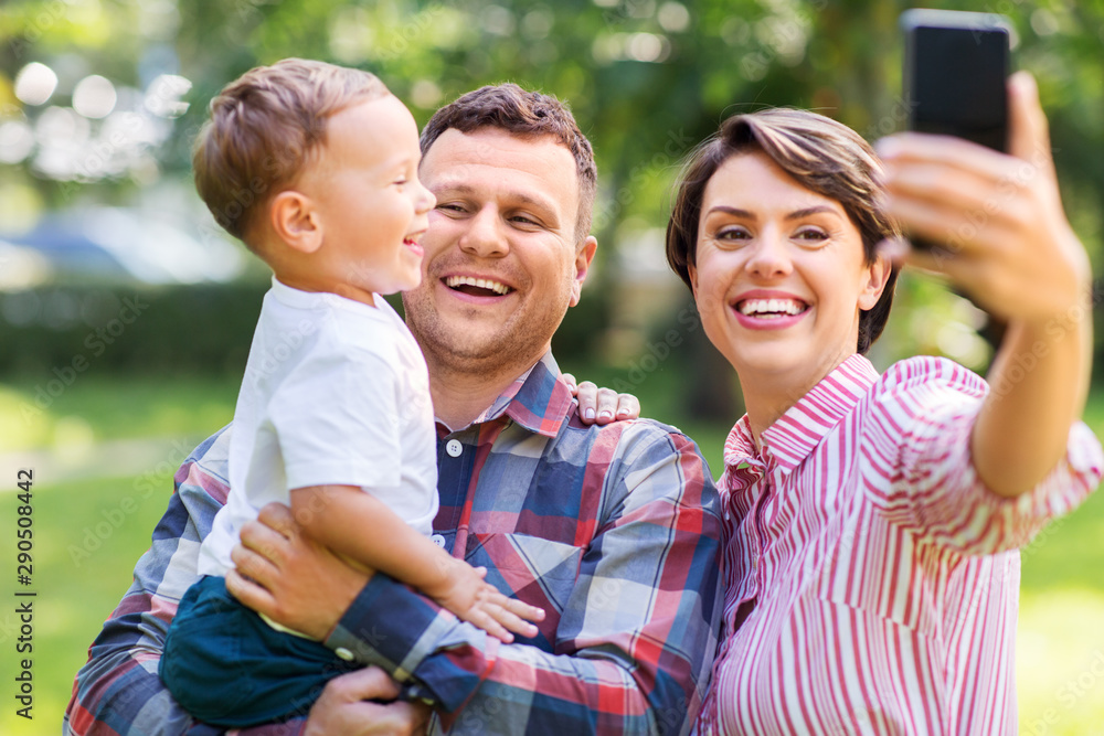 family, leisure and people concept - happy mother, father and little son taking selfie by smartphone at summer park family, leisure and people concept - happy mother, father and little son taking selfie by smartphone at summer park