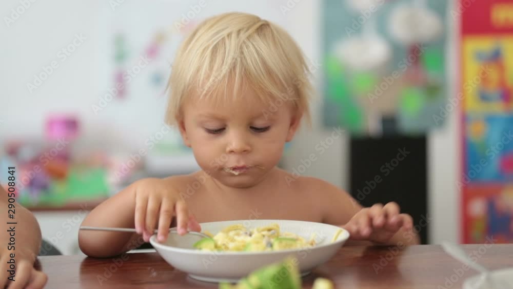 Sweet toddler boy, eating spaghetti at home, making a mess and having fun playing with them Sweet toddler boy, eating spaghetti at home, making a mess and having fun playing with them