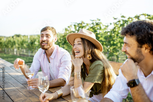 Foto Group of a young people drinking wine and talking together while sitting at the