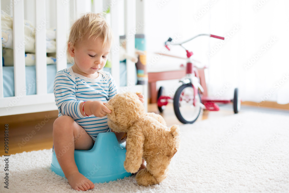 Foto de Cute toddler boy, showing his teddy bear friend how to pee in