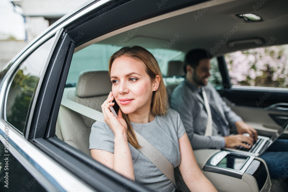 Business couple with laptop sitting on back seats in car, working. Business couple with laptop sitting on back seats in car, working.
