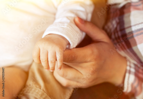 Cute little baby's hand holding mother's finger close up at home