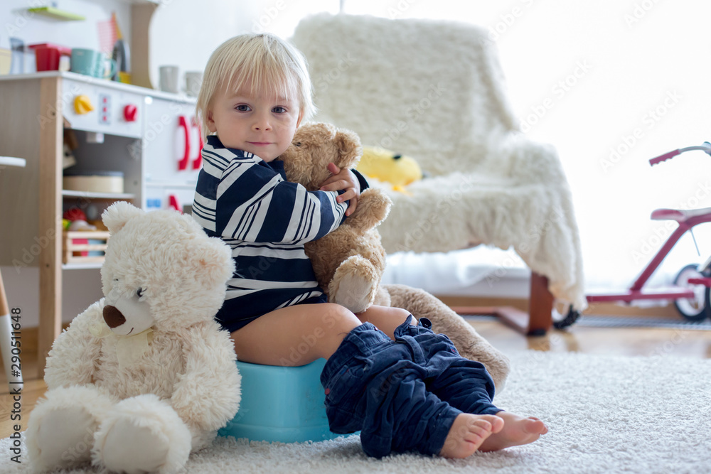 Cute toddler boy, potty training, playing with his teddy bear Cute toddler boy, potty training, playing with his teddy bear
