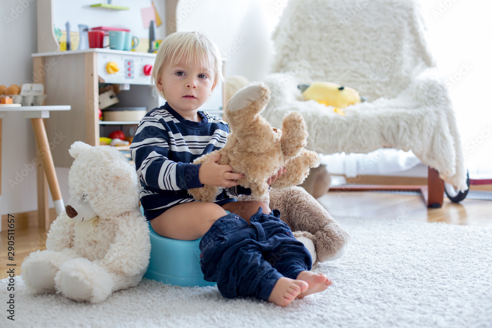 Cute toddler boy, potty training, playing with his teddy bear Cute toddler boy, potty training, playing with his teddy bear
