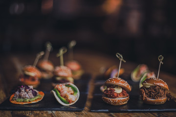 A close up shot of a selection of canape dishes. Concept of catering, hospitality and lifestyle. Small snacks and nibbles served on black slates for a private reception.