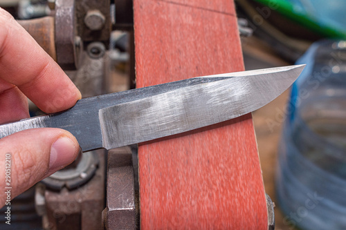 Grinding polishing sharpening knife blade on the belt grinder sander equipment. Knife making.