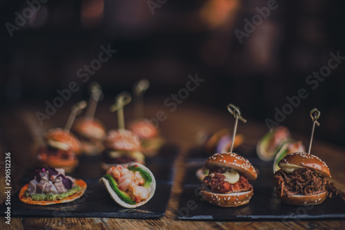 A close up shot of a selection of canape dishes. Concept of catering, hospitality and lifestyle. Small snacks and nibbles served on black slates for a private reception. photo