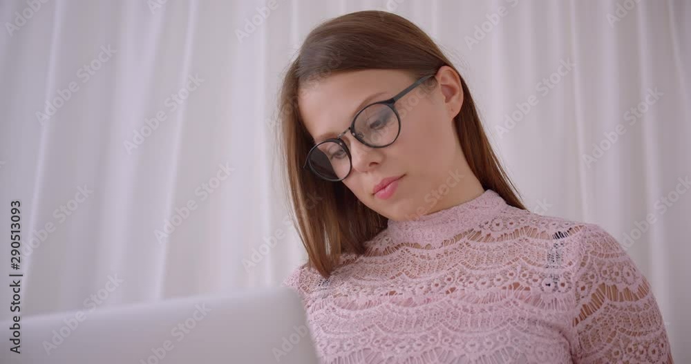 Closeup portrait of young attractive caucasian businesswoman using laptop looking at camera smiling cheerfully sitting on couch indoors Closeup portrait of young attractive caucasian businesswoman using laptop looking at camera smiling cheerfully sitting on couch indoors