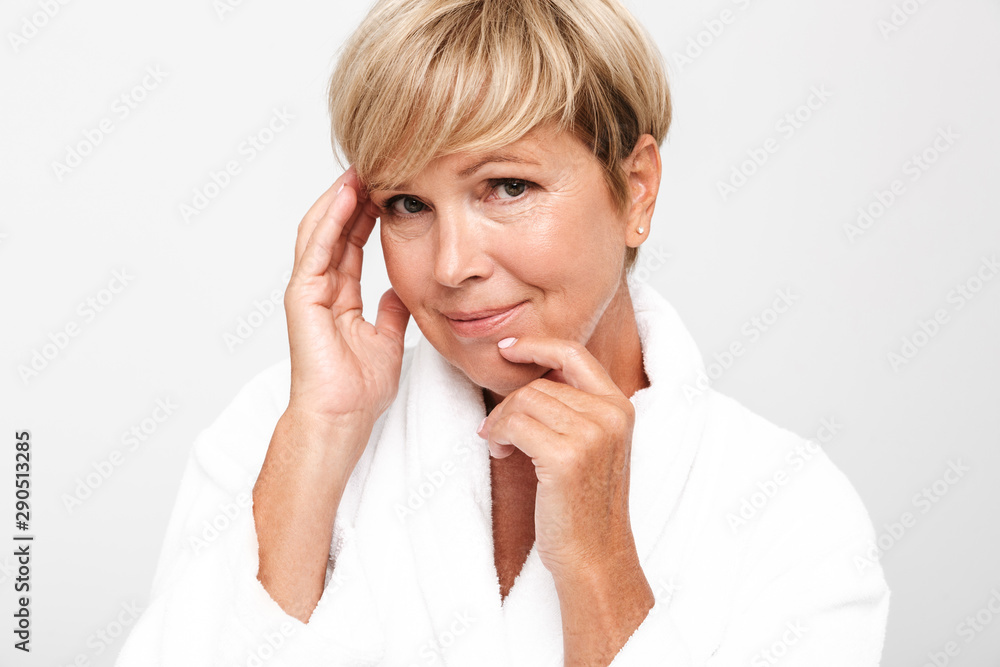 Image of middle-aged woman wearing white housecoat touching her face Image of middle-aged woman wearing white housecoat touching her face
