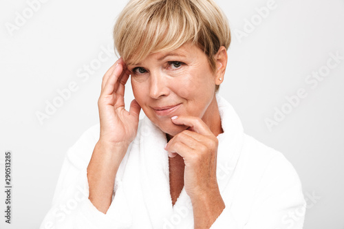 Image of middle-aged woman wearing white housecoat touching her face