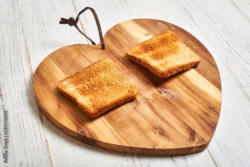 Toasted white bread toast on a wooden background in the shape of a heart. photo