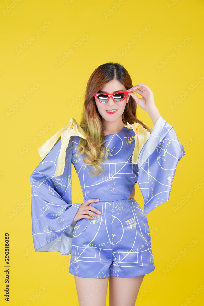 Fashion girl dress up with a hand gesture on a yellow background.