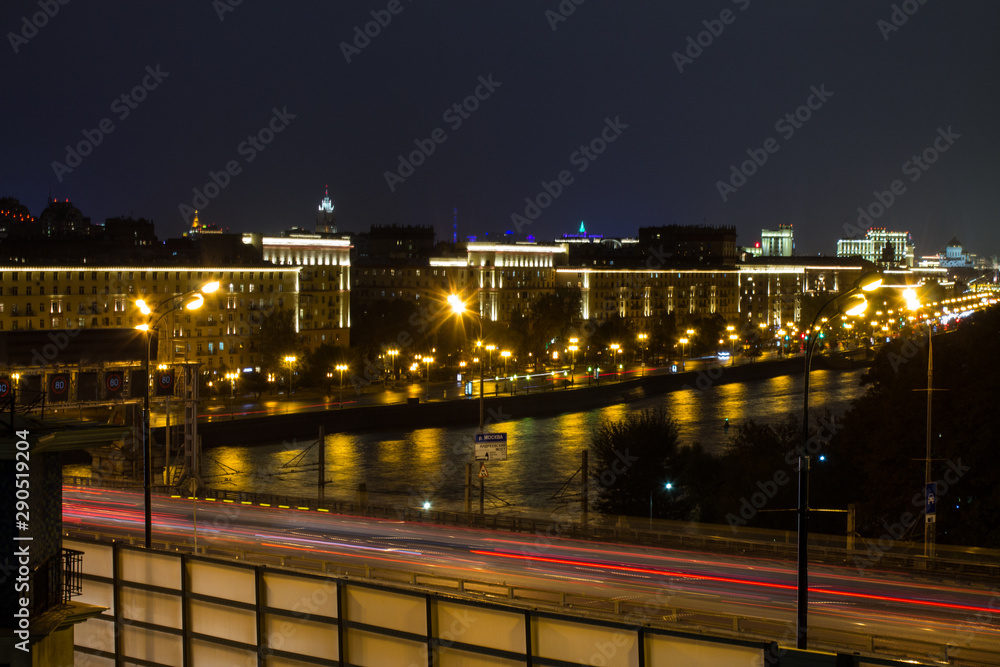 urban view of the railway via the metal bridge next to the freeway in the background of the night sky in Moscow Russia