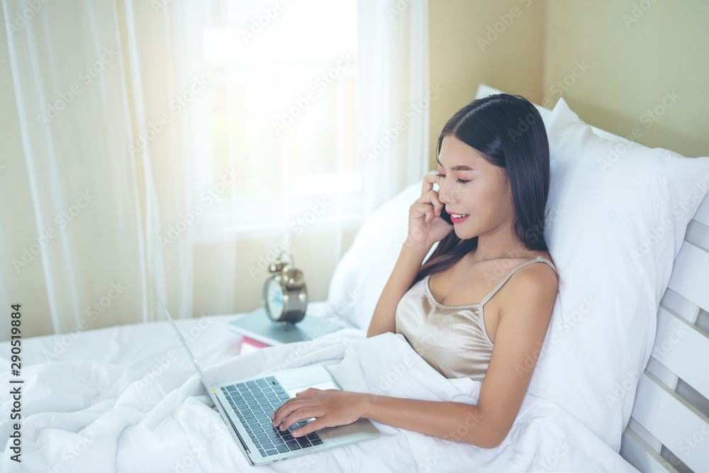 A beautiful Asian woman relaxes and works with a laptop computer, reading at home. A beautiful Asian woman relaxes and works with a laptop computer, reading at home.