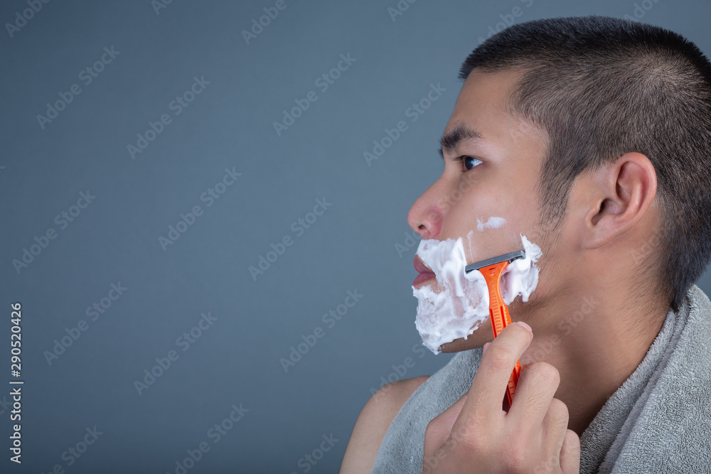 Shaving handsome guy shaved on the face on a gray background. Shaving handsome guy shaved on the face on a gray background.