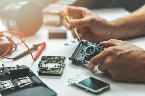 electronic repair service - technician repairing digital camera in office