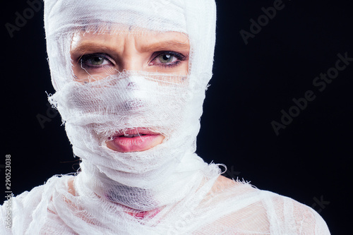 Fototapeta Glamorous mummy woman in bandages all over her body in studio black background