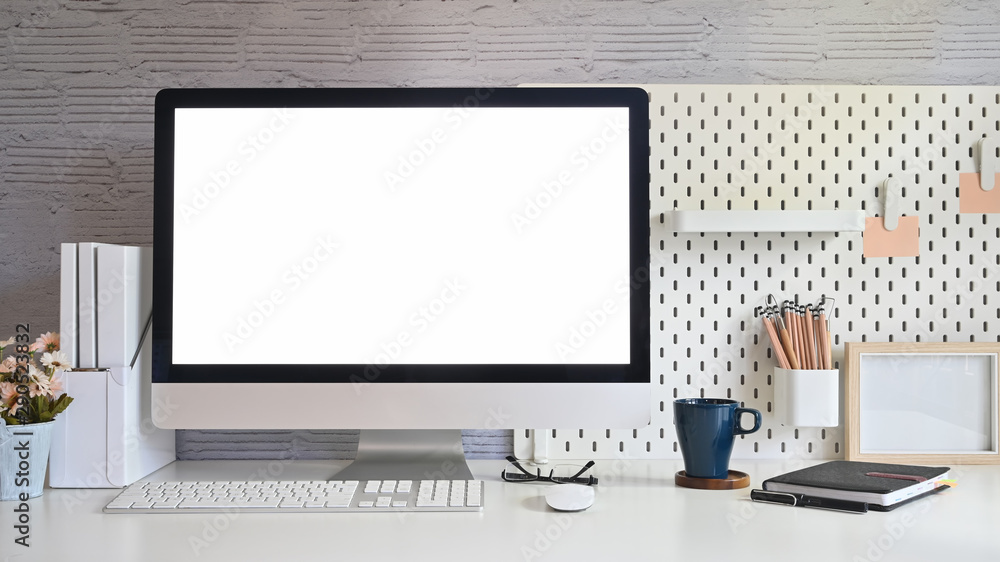 Fototapeta premium Workspace and blank screen desktop computer.Mockup desktop computer, coffee mug, plant and office accessories on white desk.