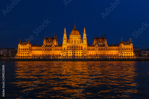 The Hungarian Parliament Building, a notable landmark of Hungary in Budapest. View of the main facade illuminated above the Danube river at night.