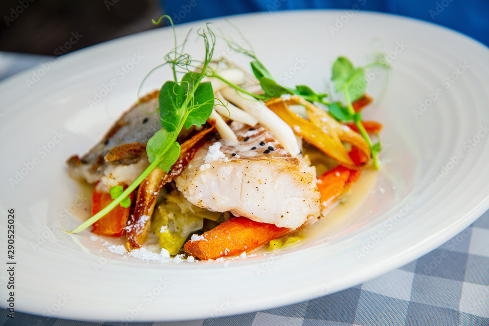 Delicious fillet of cod fish with carrots, leeks and mushrooms in white plate ready to be served Delicious fillet of cod fish with carrots, leeks and mushrooms in white plate ready to be served