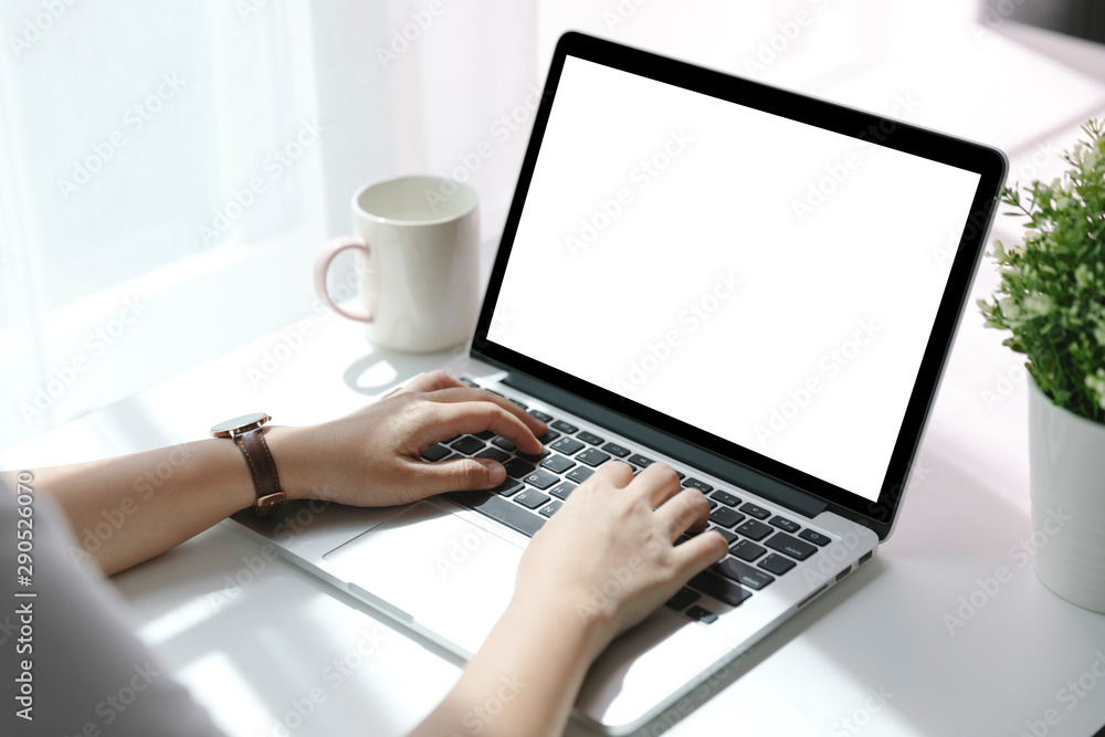 Young women using laptop with blank screen at table in the office, Back view of business women hands busy using laptop at office desk. Young women using laptop with blank screen at table in the office, Back view of business women hands busy using laptop at office desk.