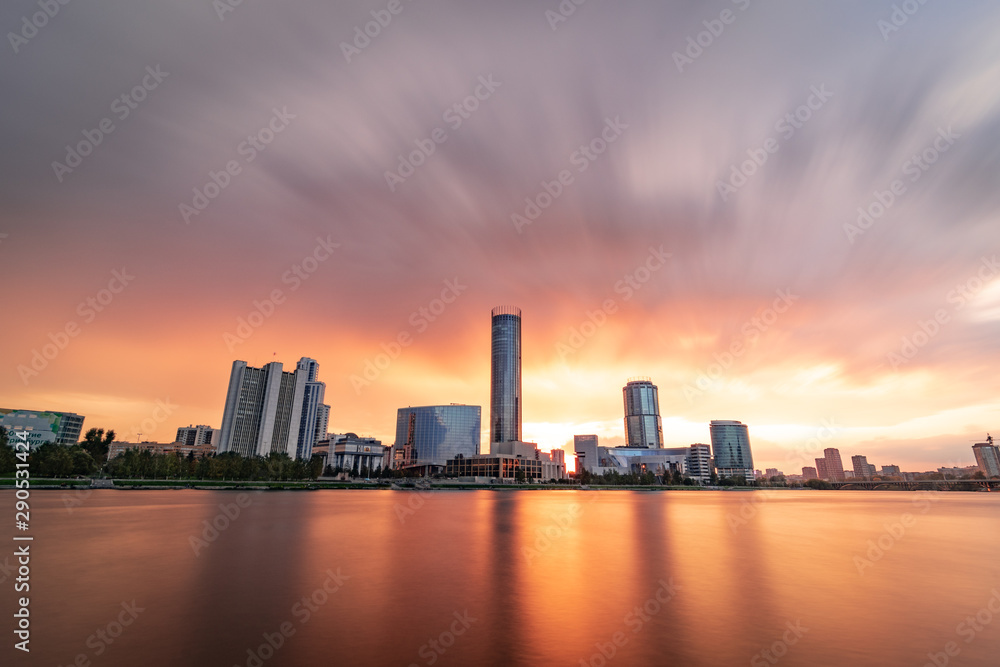 Beautiful cloudy sunset at the city pond. Long Exposure cityscape of Yekaterinburg, Russia with skyscrappers reflecting in water