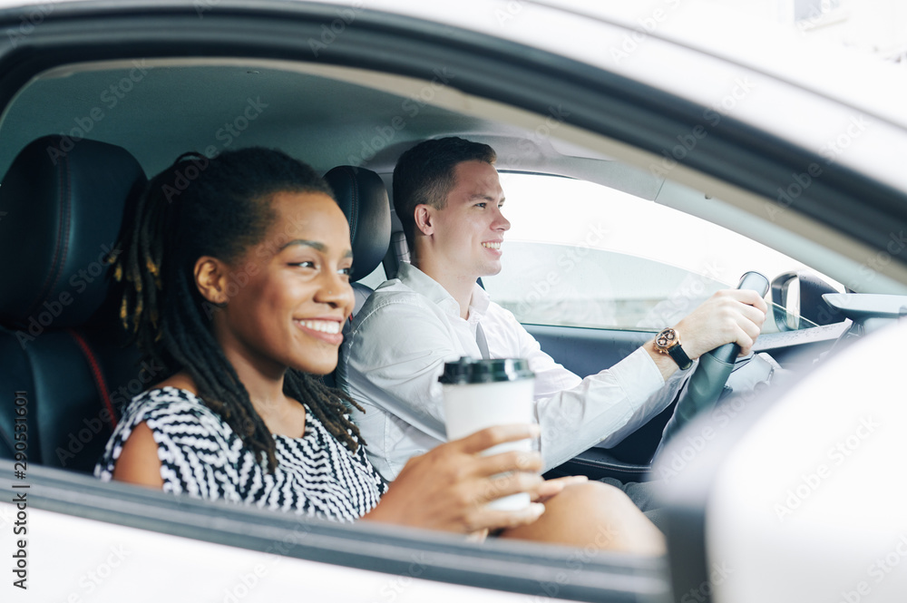 Happy African girl drinking coffee and smiling while sitting in the car with young man Happy African girl drinking coffee and smiling while sitting in the car with young man