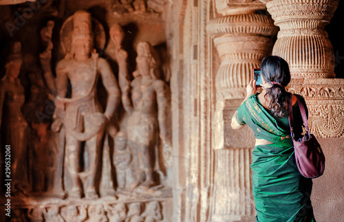 Photography Woman making picture by iphone inside the 6th century Hindu temple with caves